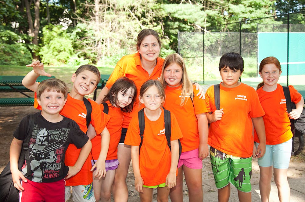Group of children and one adult standing together outdoors