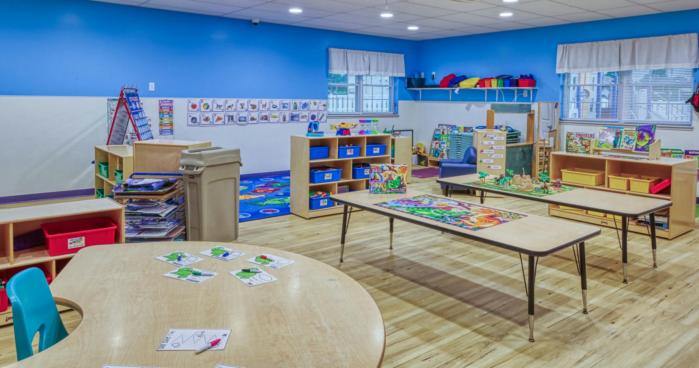 An empty early childhood classroom with blue walls and colorful learning stations