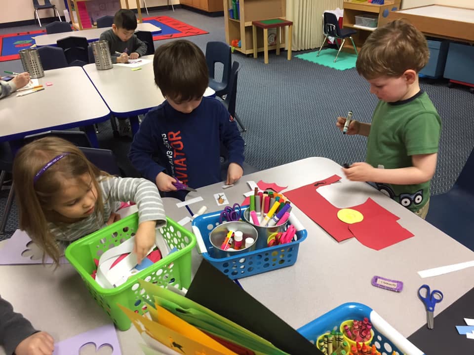 Children doing crafts at a table in a classroom
