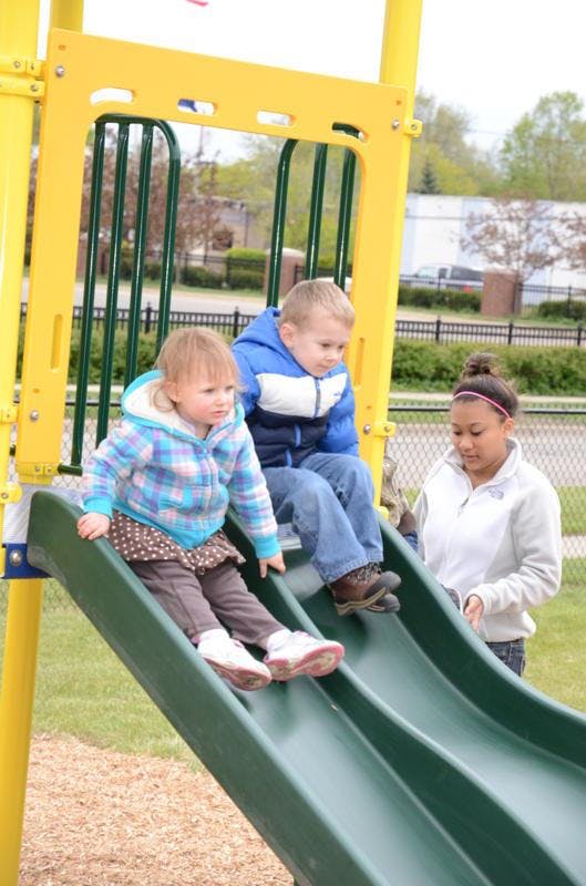 Two children and a teen on a playground slide