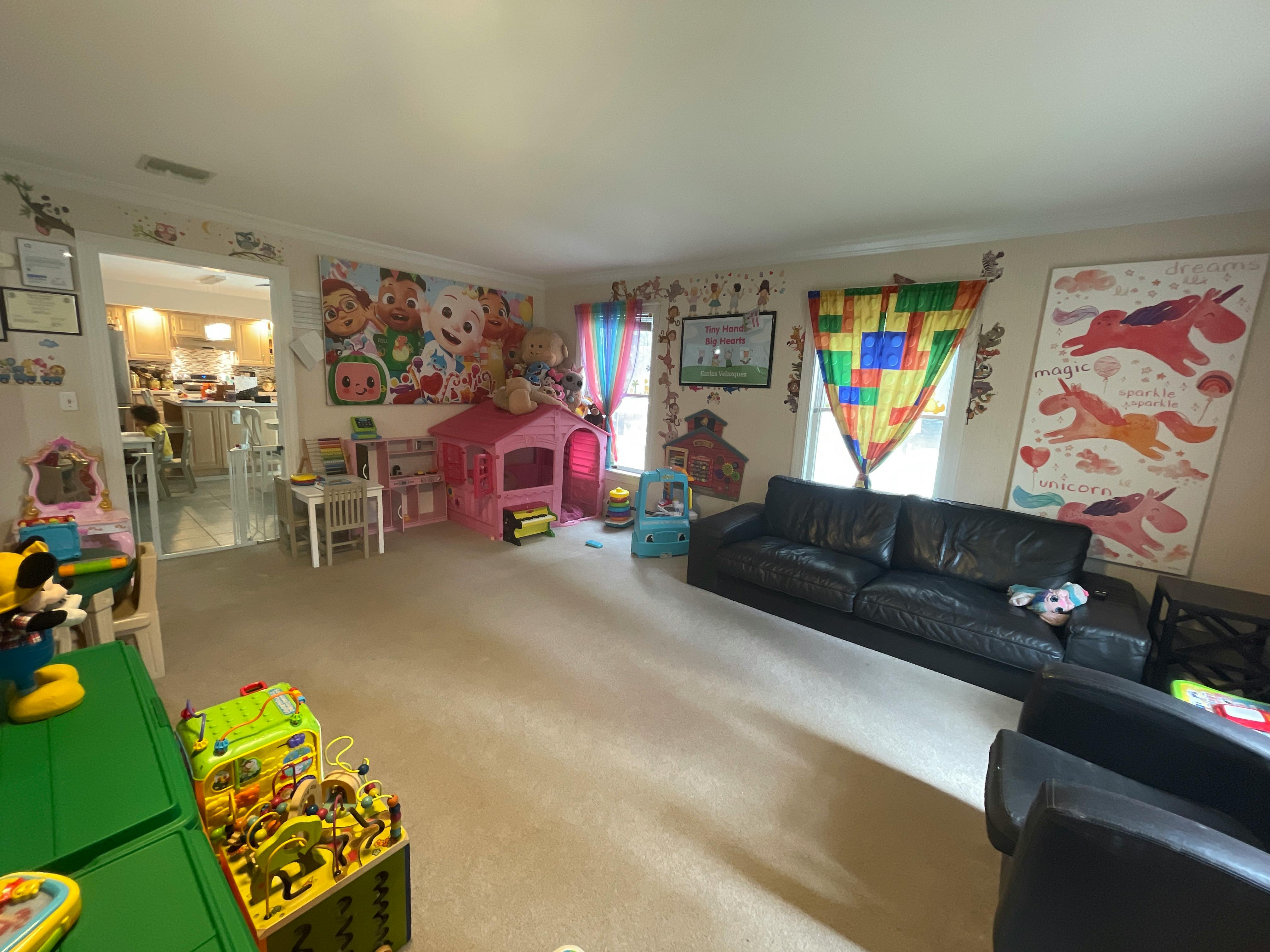 Living room with a black sofa, playhouse, and colorful decorations