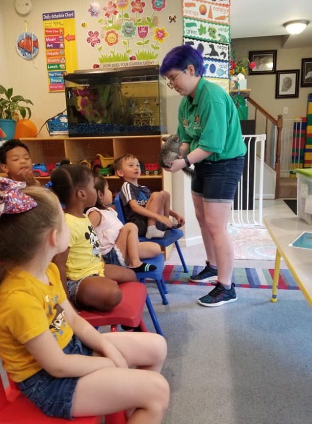 Person holding an animal for a group of children in a classroom