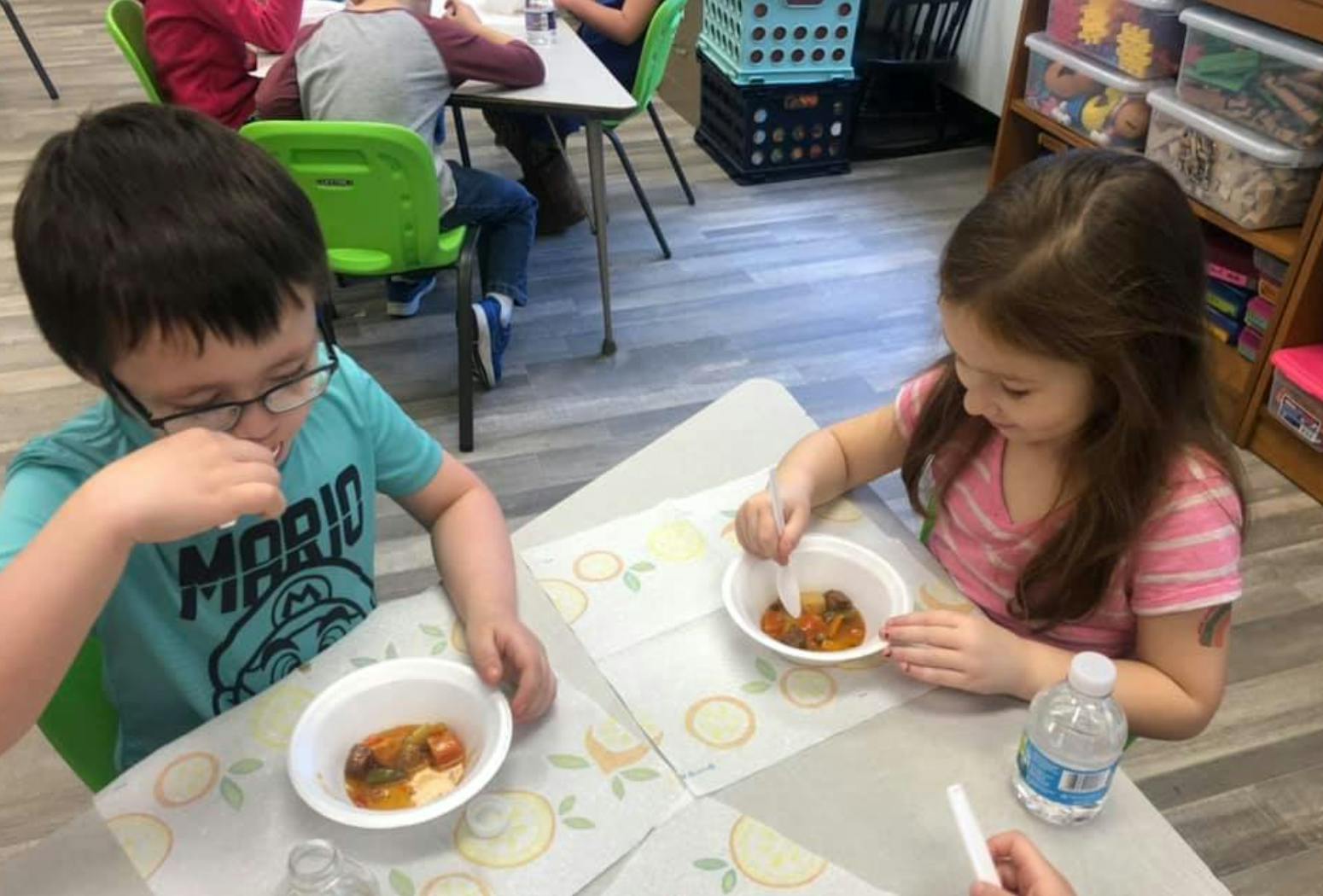 Two children eating from bowls at a table