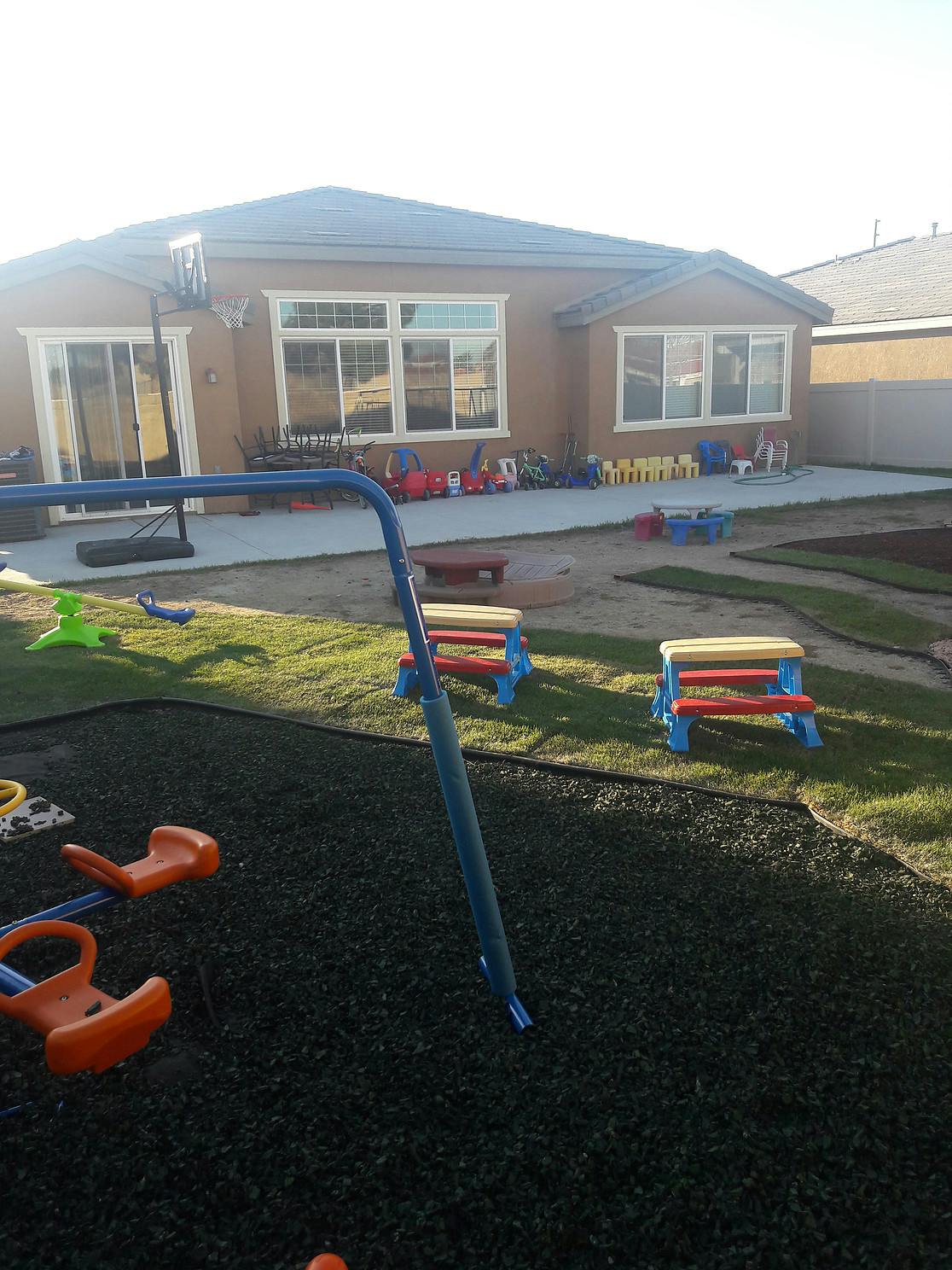 Backyard with a house, playground equipment, and small picnic tables