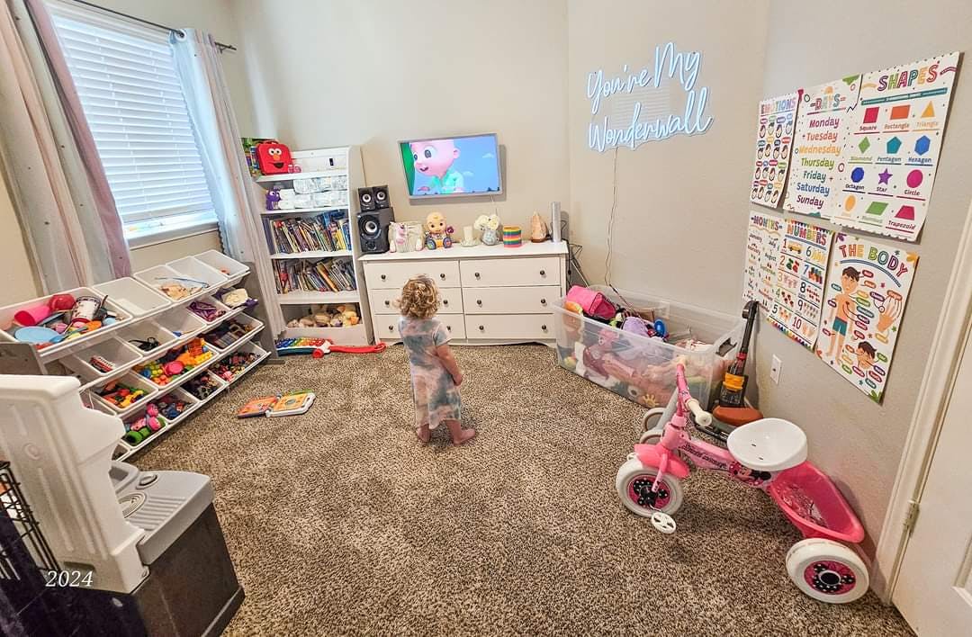 Child standing in a playroom with toys and furniture