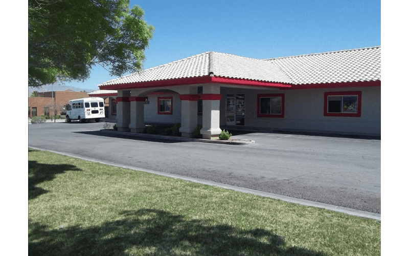 Single-story building with a red and white roof and a white bus in the parking lot