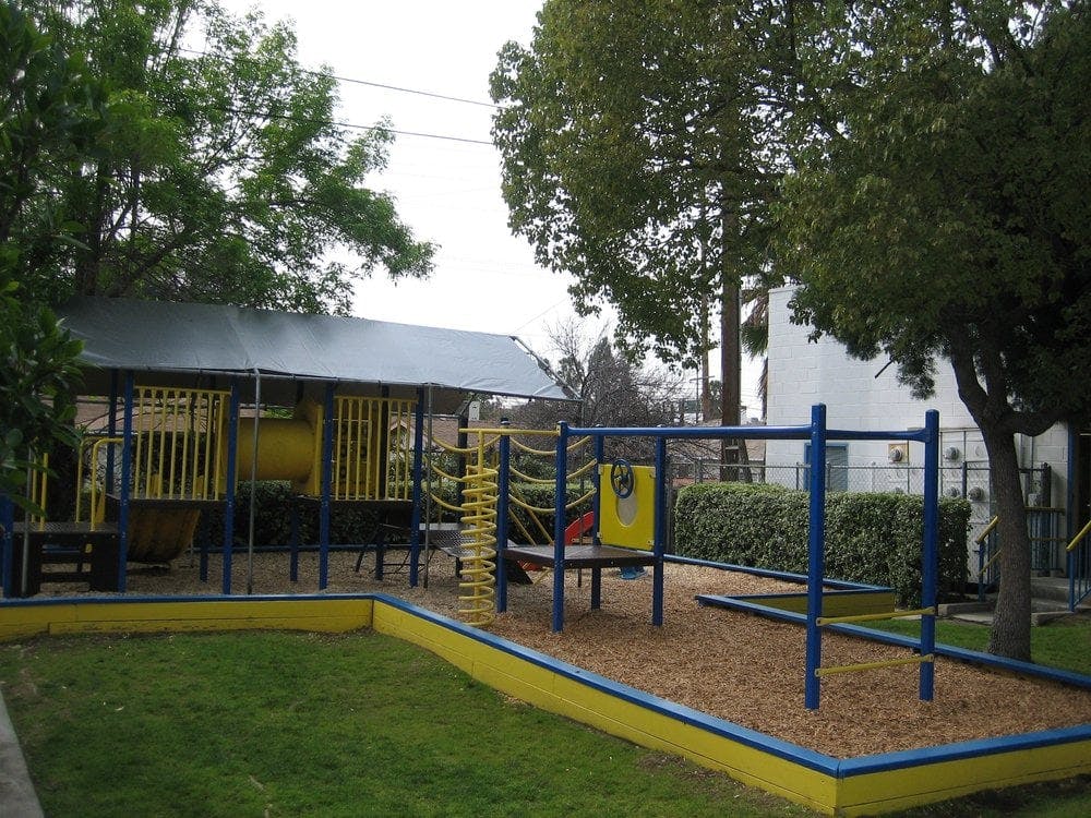 Playground with yellow and blue equipment and a small covered structure