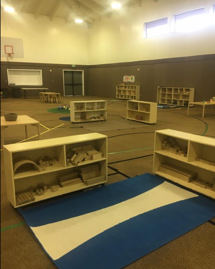 Gymnasium set up with shelves of educational materials and a blue mat