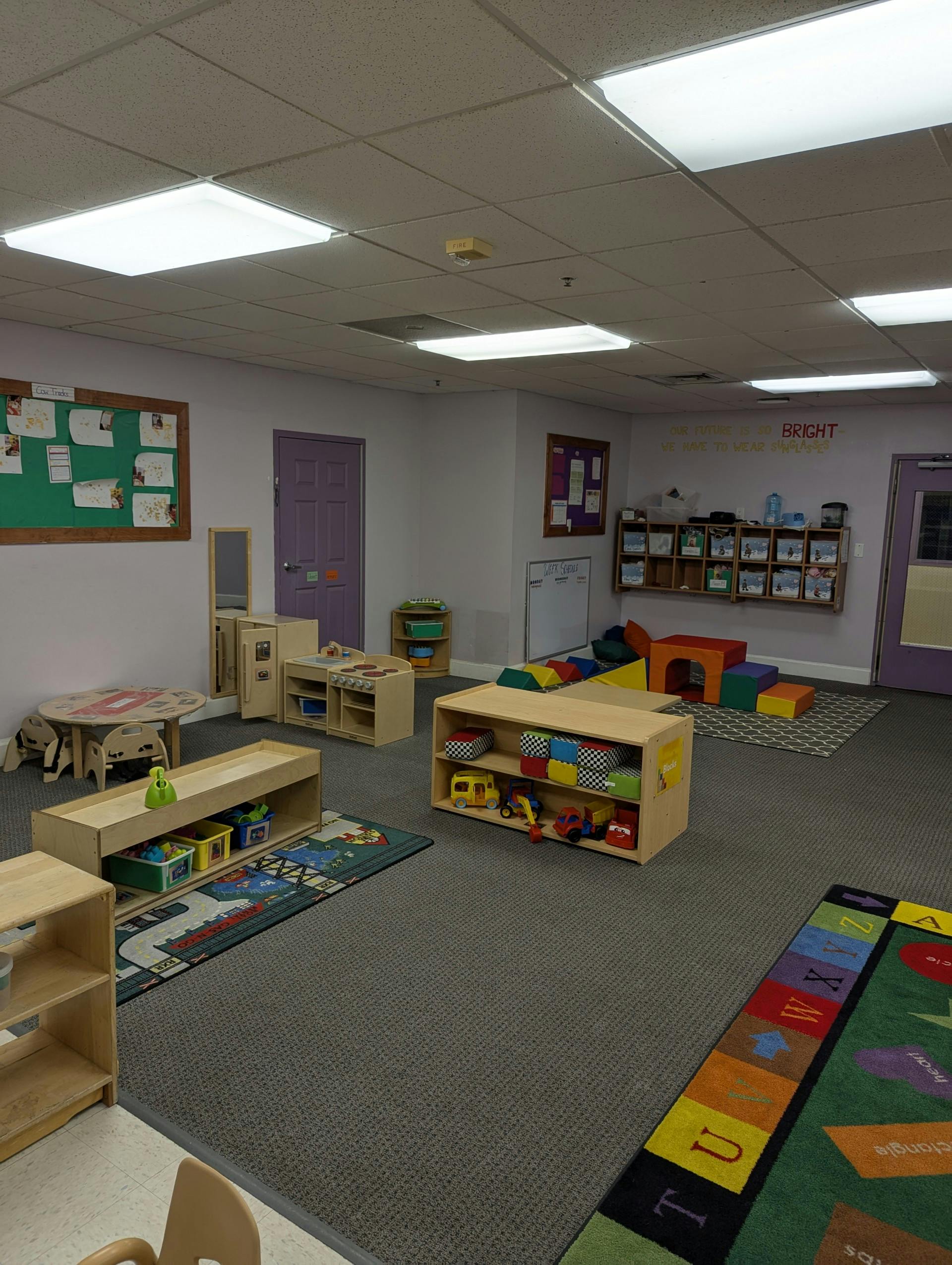 Empty classroom with colorful rugs, toys, and small tables