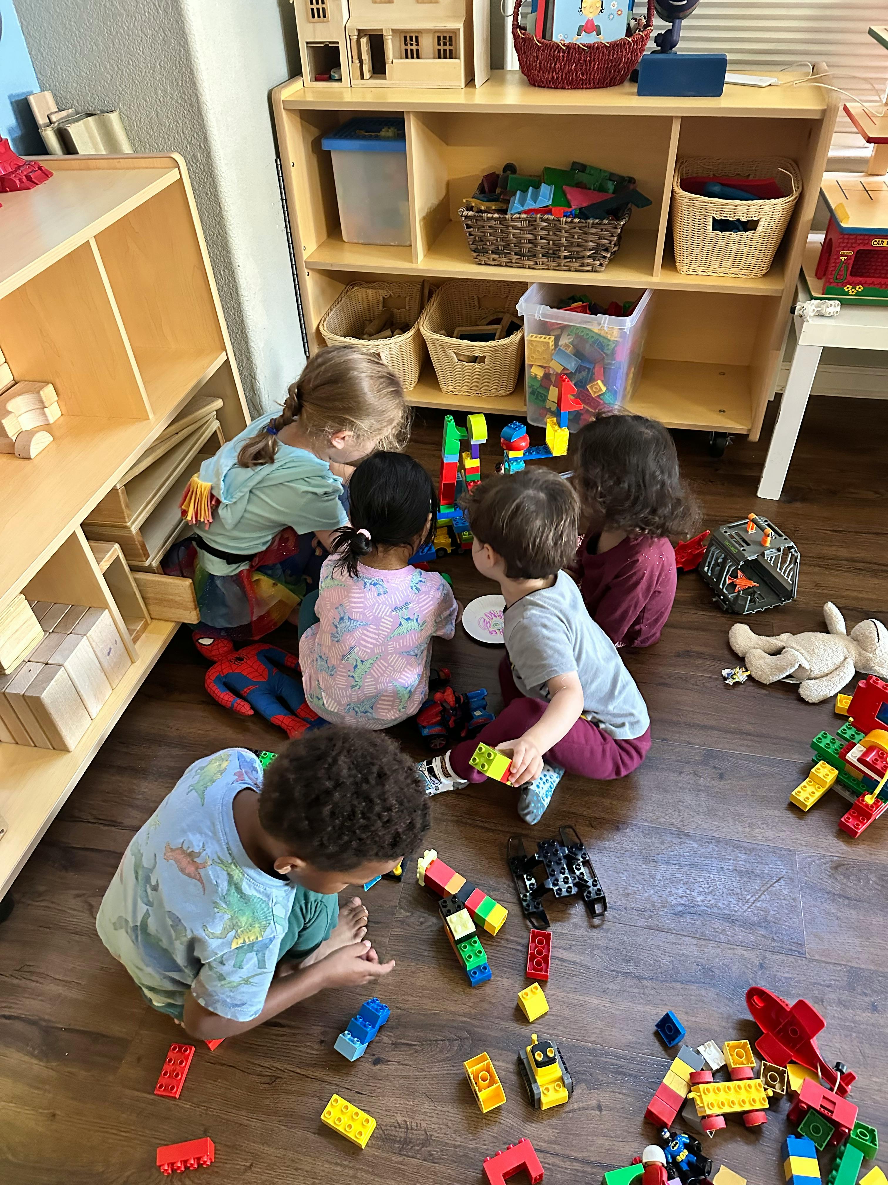 Children playing with colorful building blocks on a wooden floor