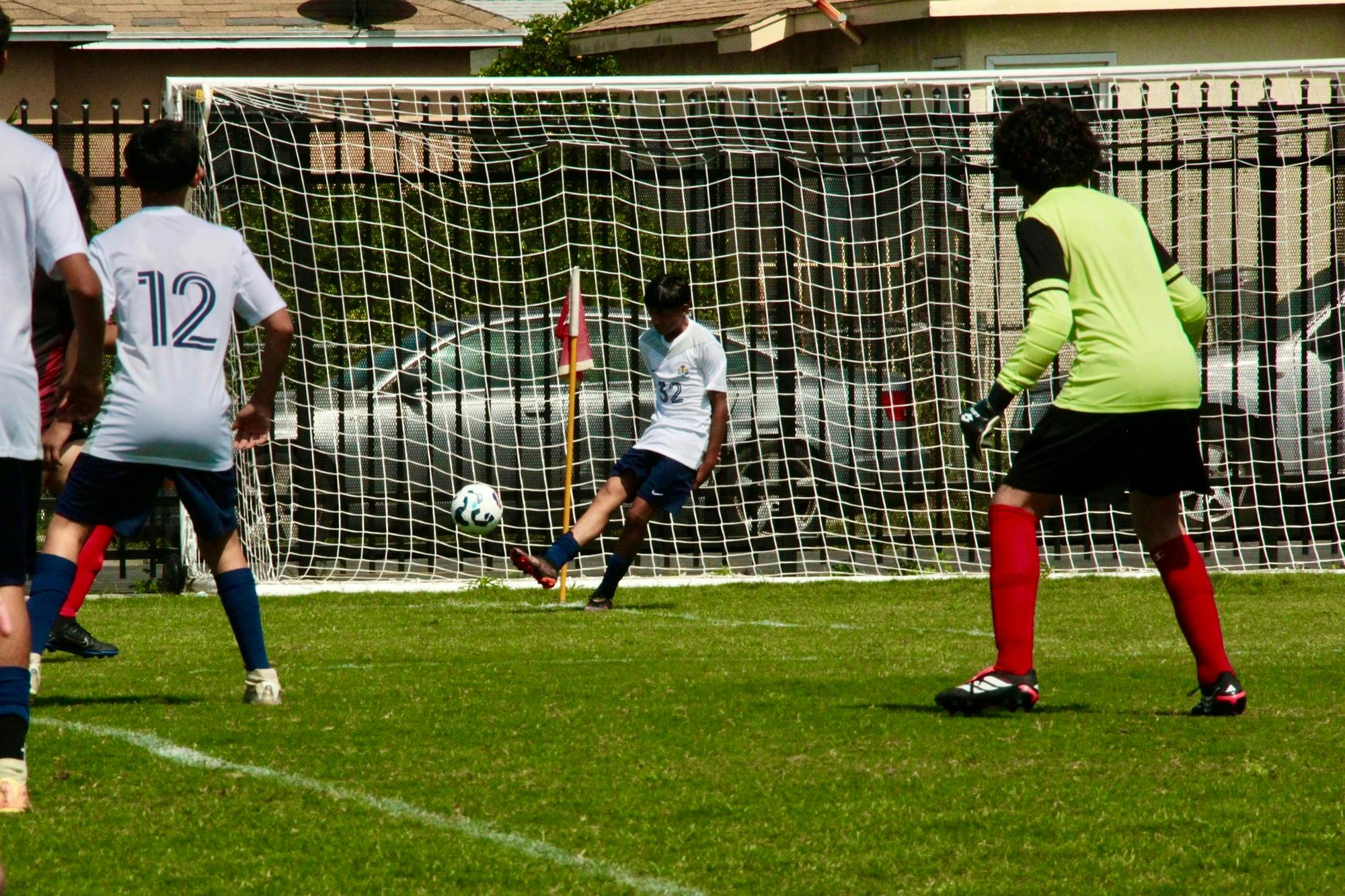 Soccer player kicking a ball into a goal