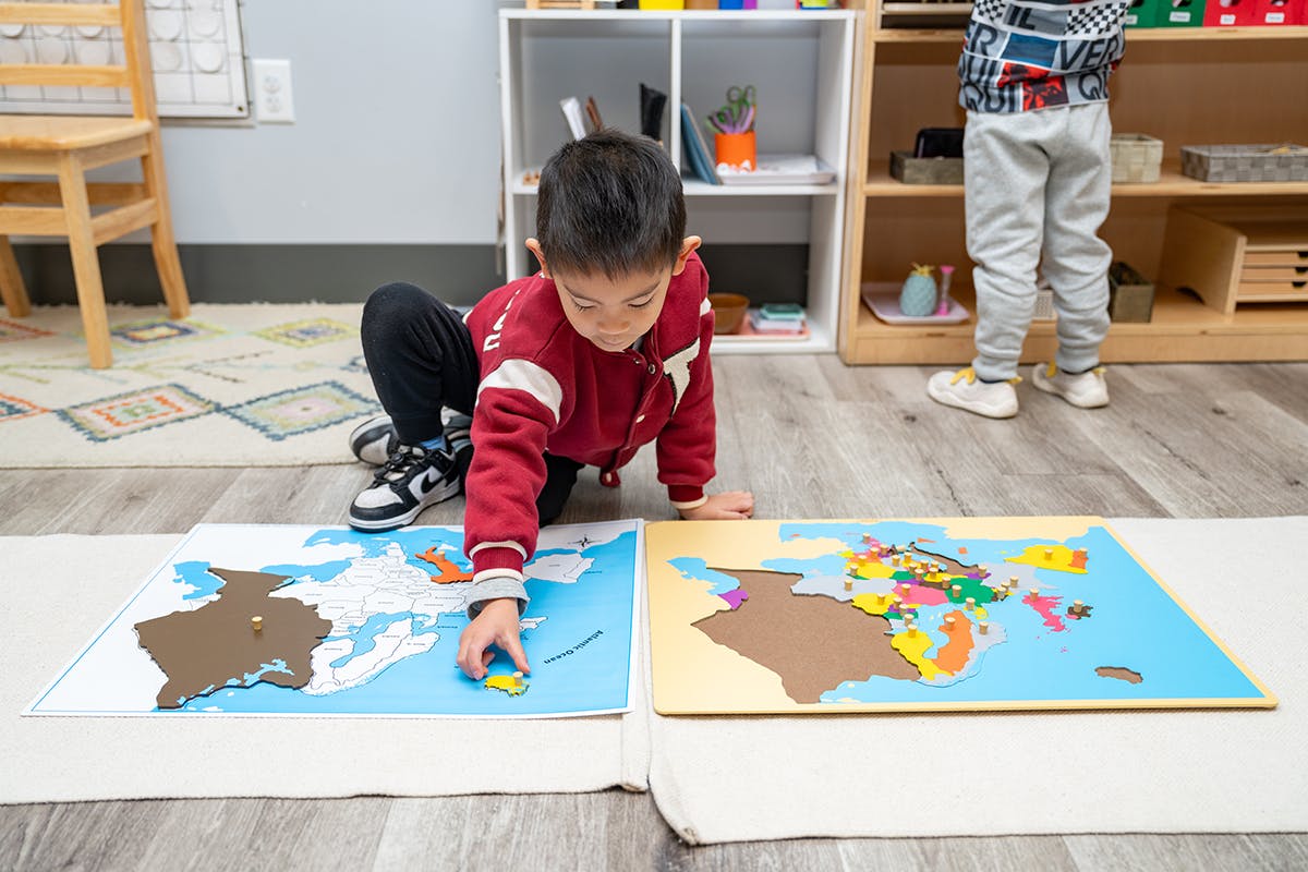 Child on floor playing with a world map puzzle