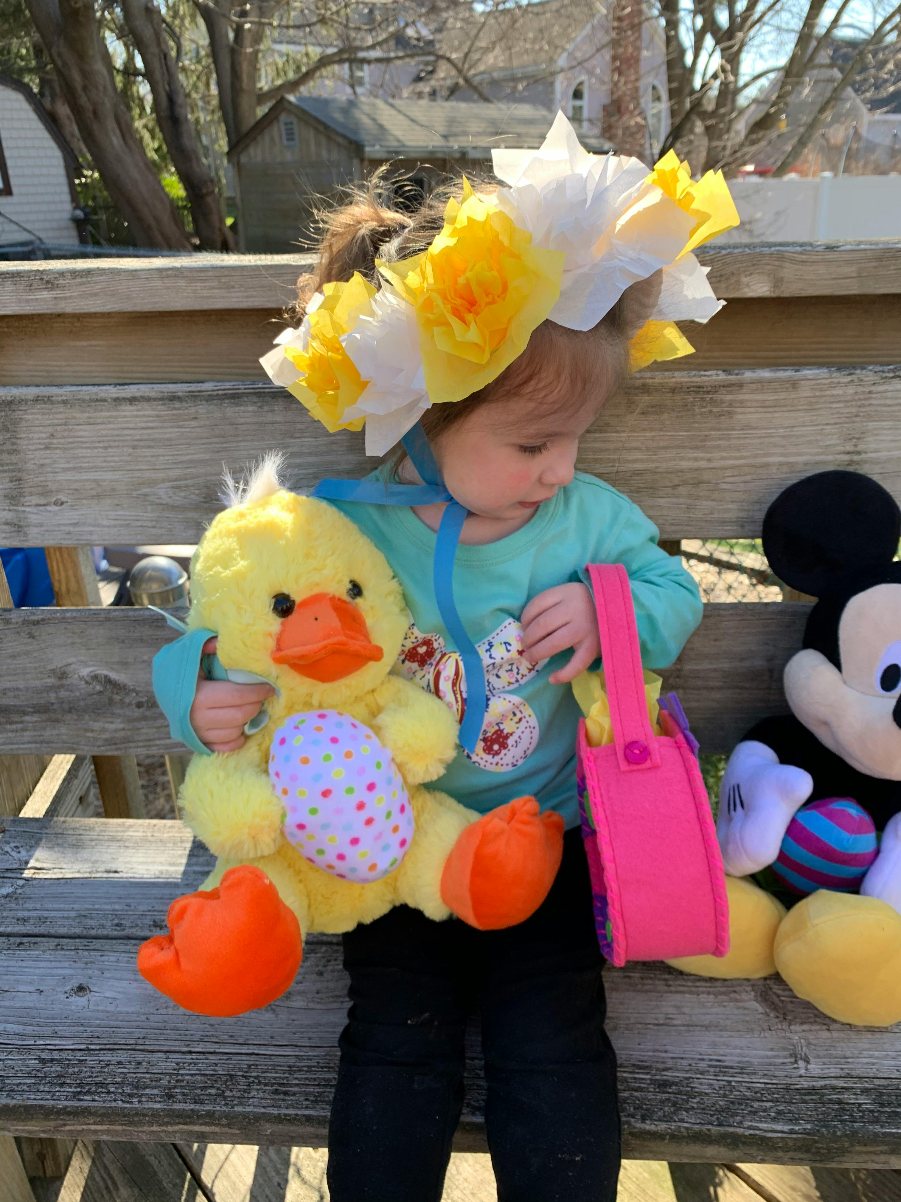 Child wearing a flower crown, holding a duck plush toy with an egg