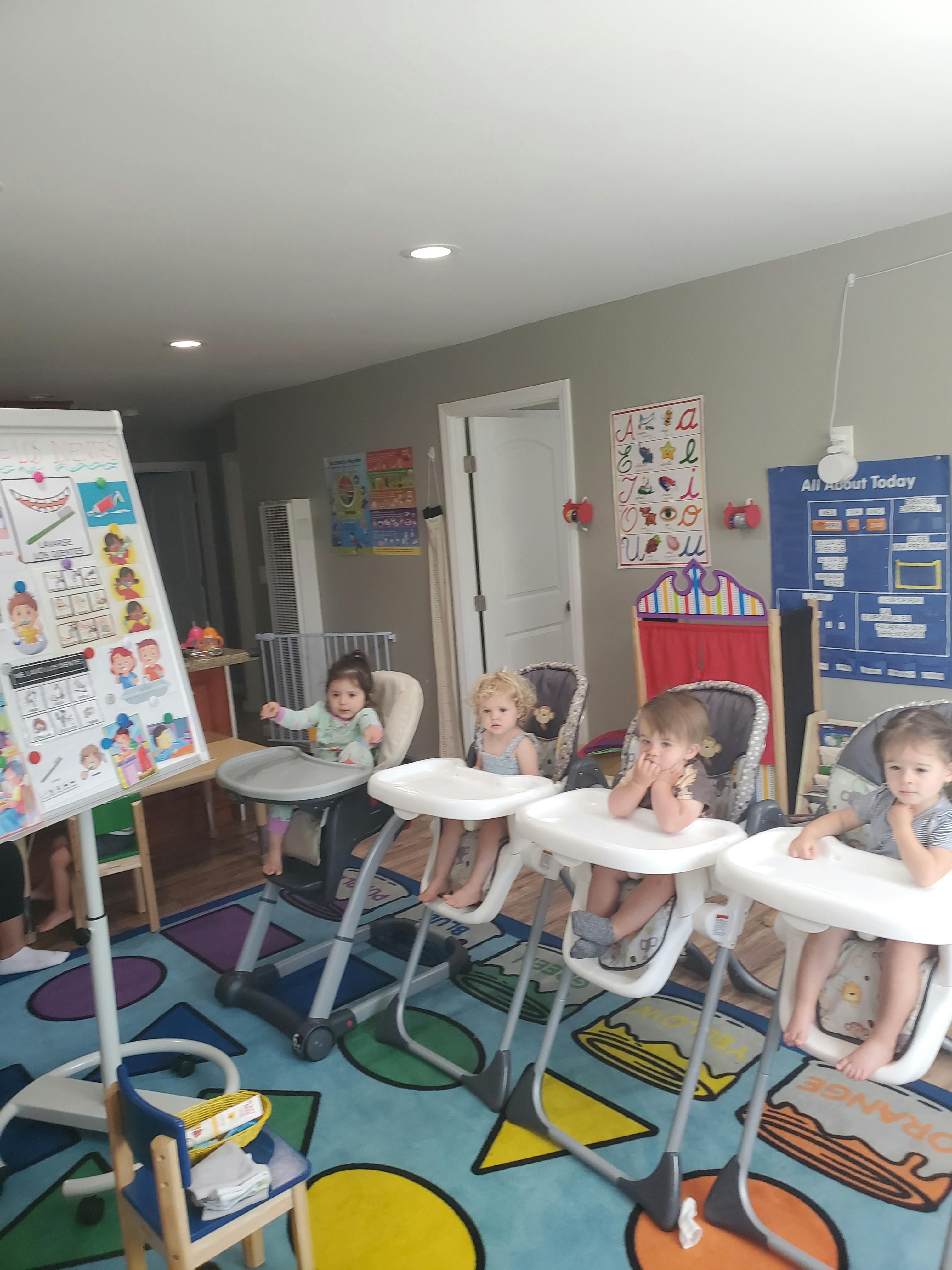 Four children sitting in high chairs in a room