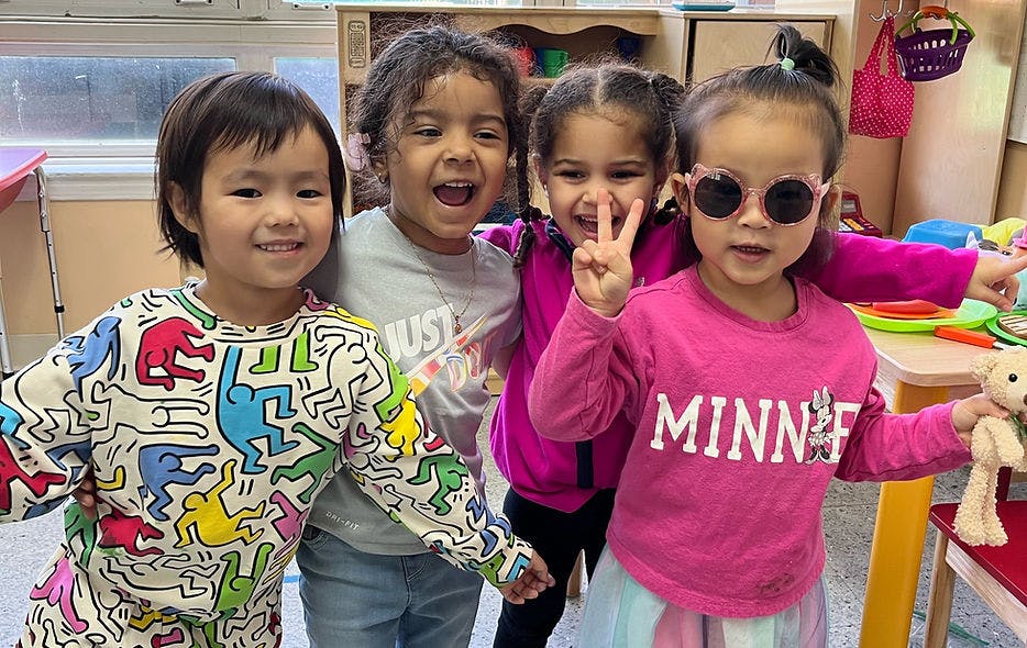 Four children smiling, one wearing sunglasses