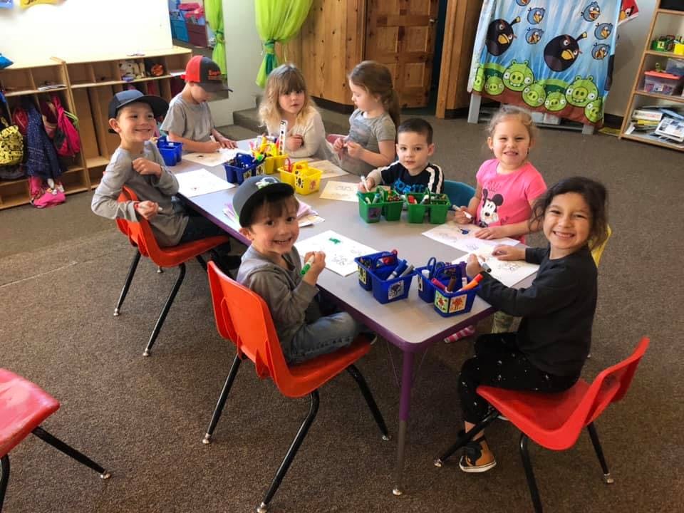 Children sitting at a table with art supplies