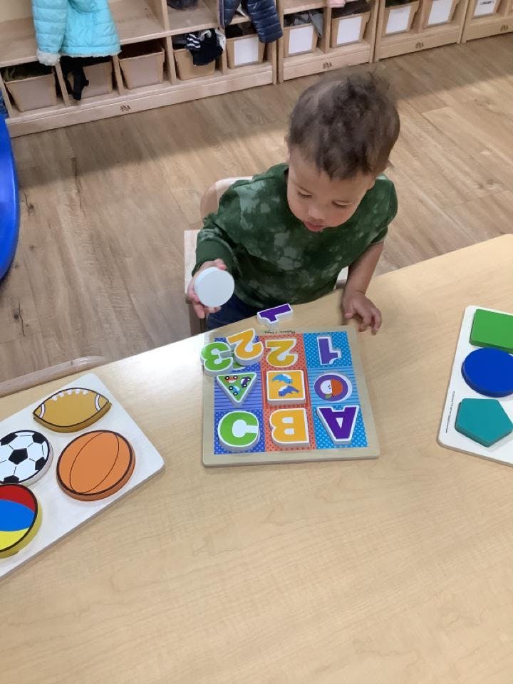 Child playing with an alphabet and number puzzle on a table