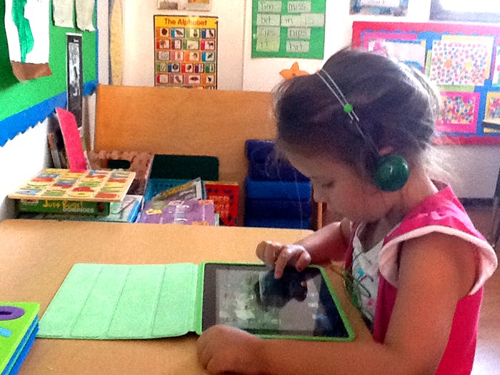 Child wearing headphones using a tablet in a classroom