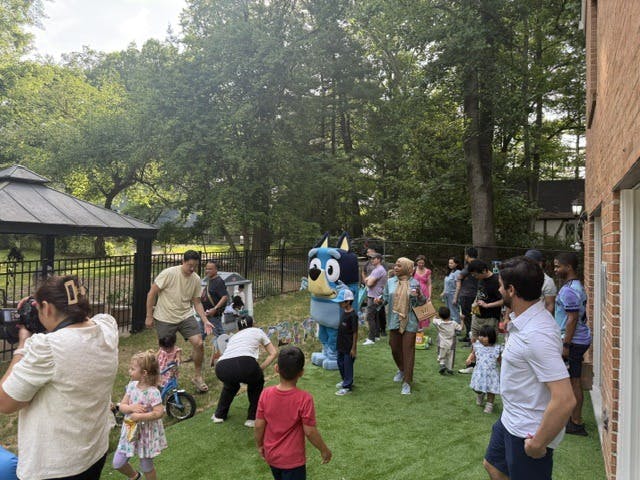 People gathered in a backyard with a person in a cartoon character costume