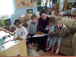 Adult reading a book to four children