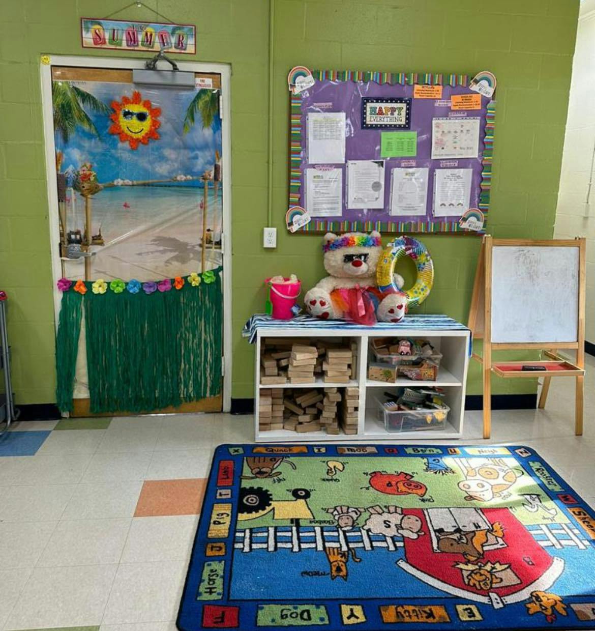 Classroom door decorated with a beach scene and a colorful rug with farm animals