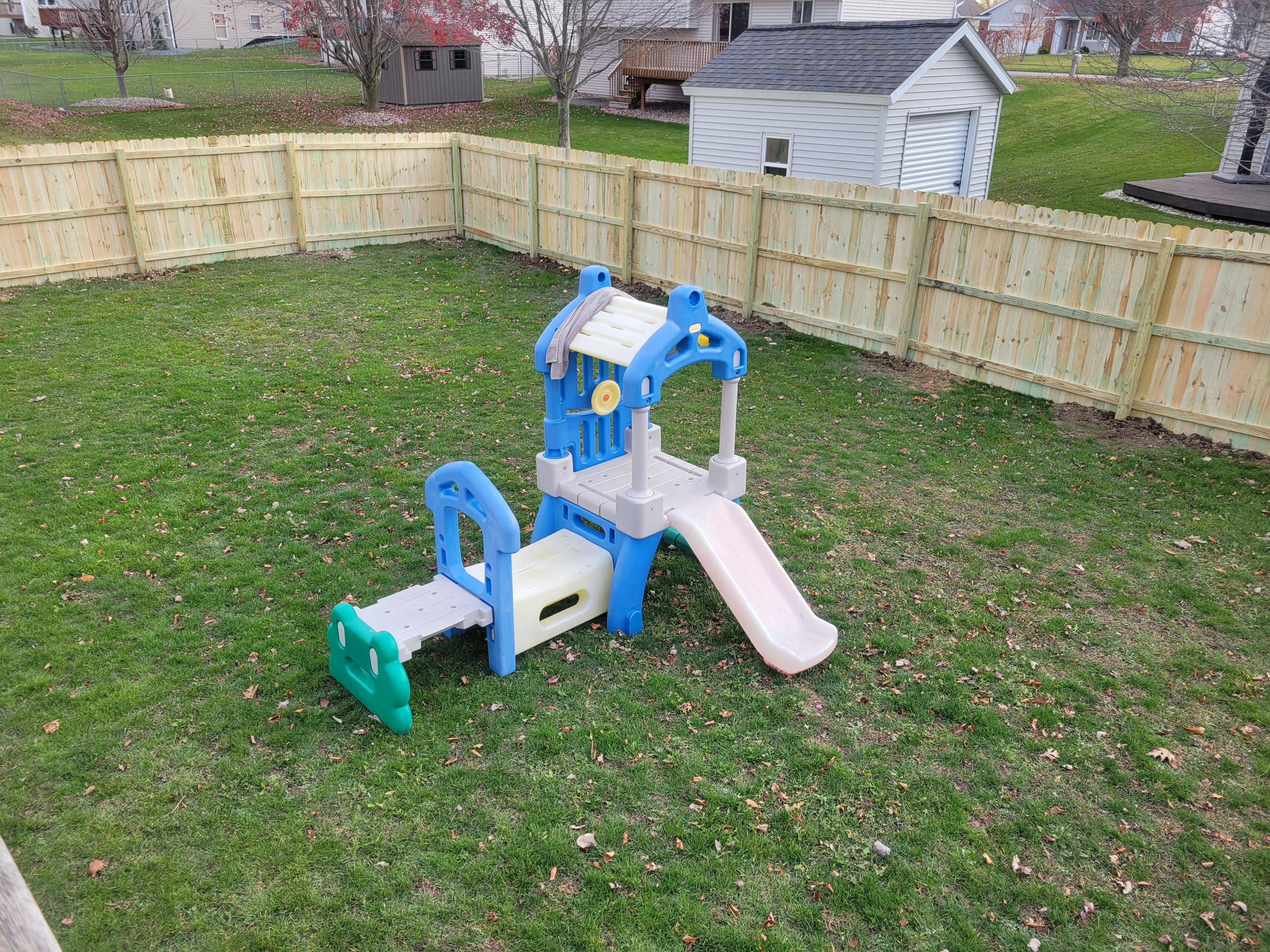 Children's play structure with slide in a grassy backyard