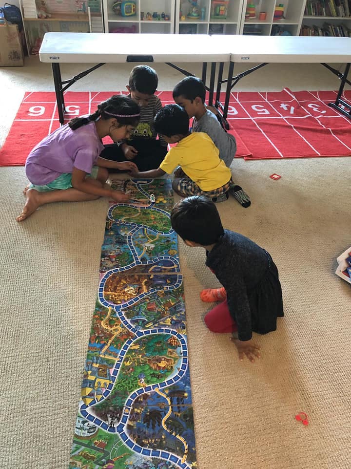 Children playing with a long floor puzzle