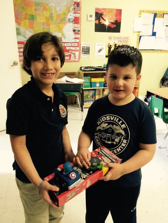Two children holding a toy boat in a classroom