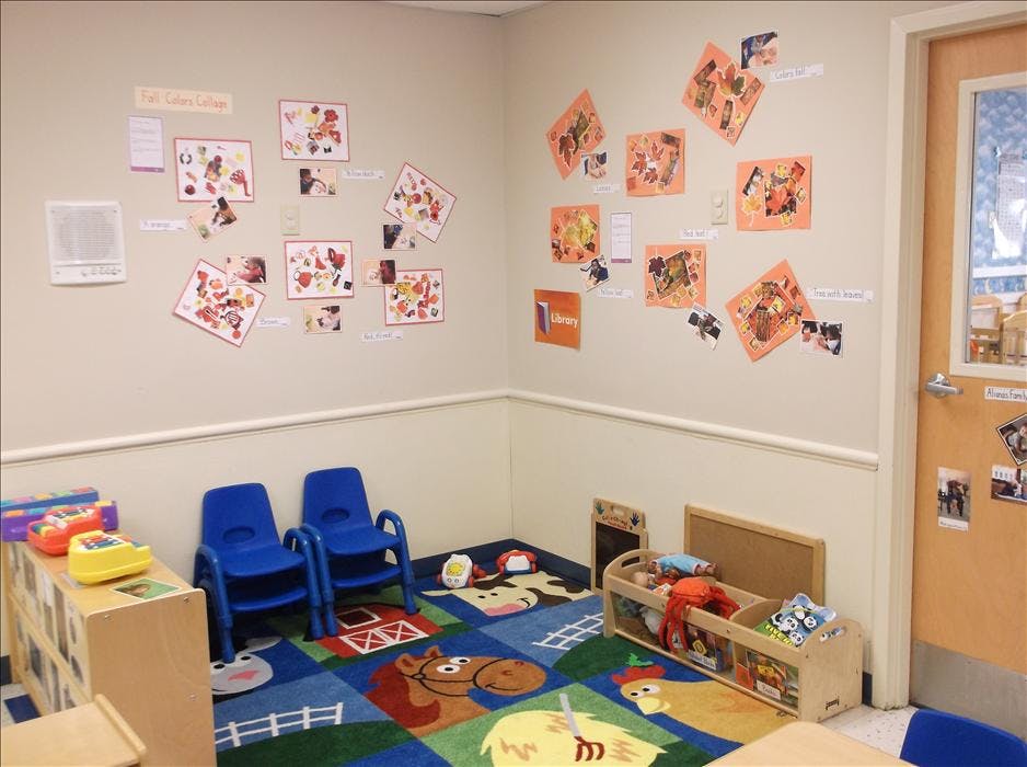 Classroom corner with colorful farm rug, children's chairs, and crafts on the wall