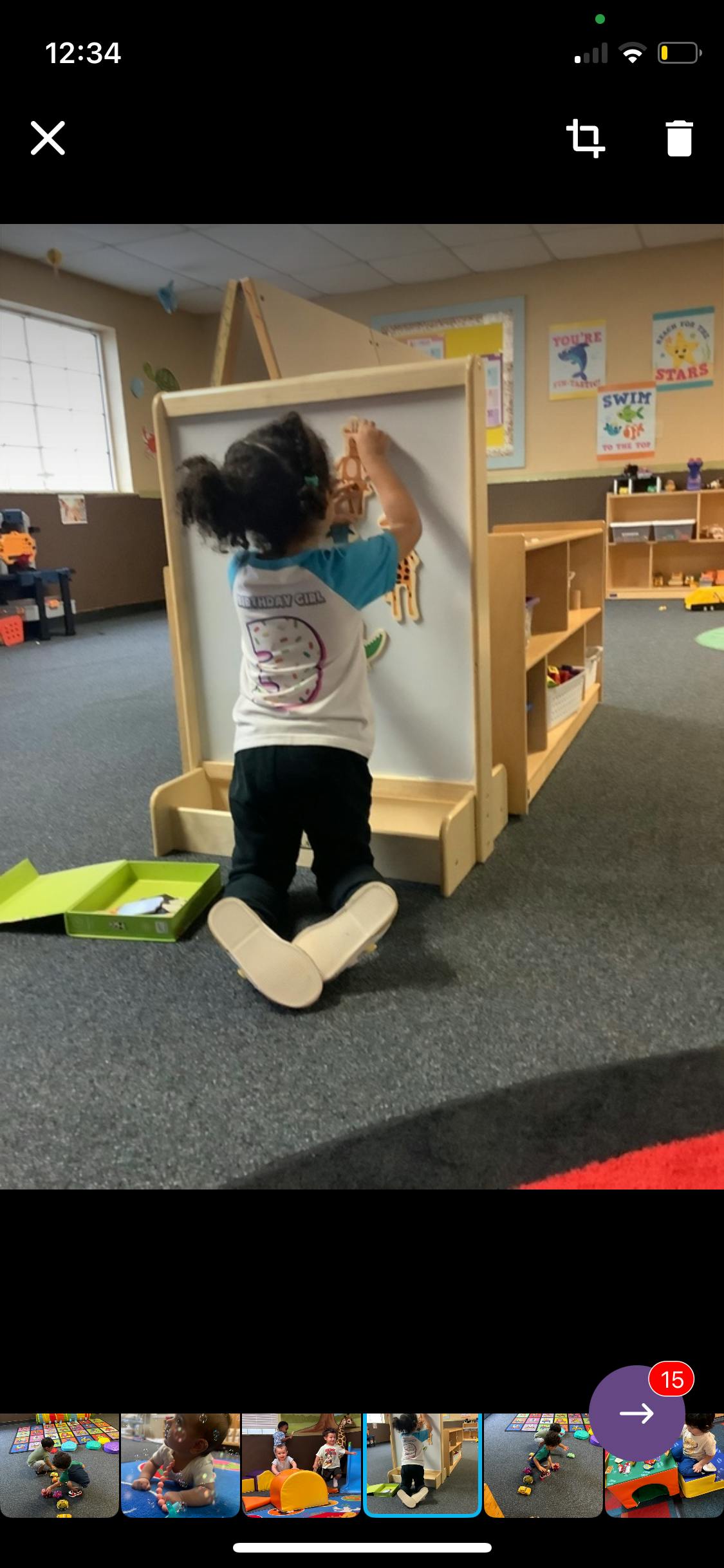 Child kneeling and playing with a magnetic board in a classroom