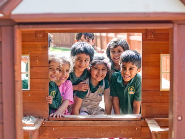 Group of children looking out from a wooden playhouse window