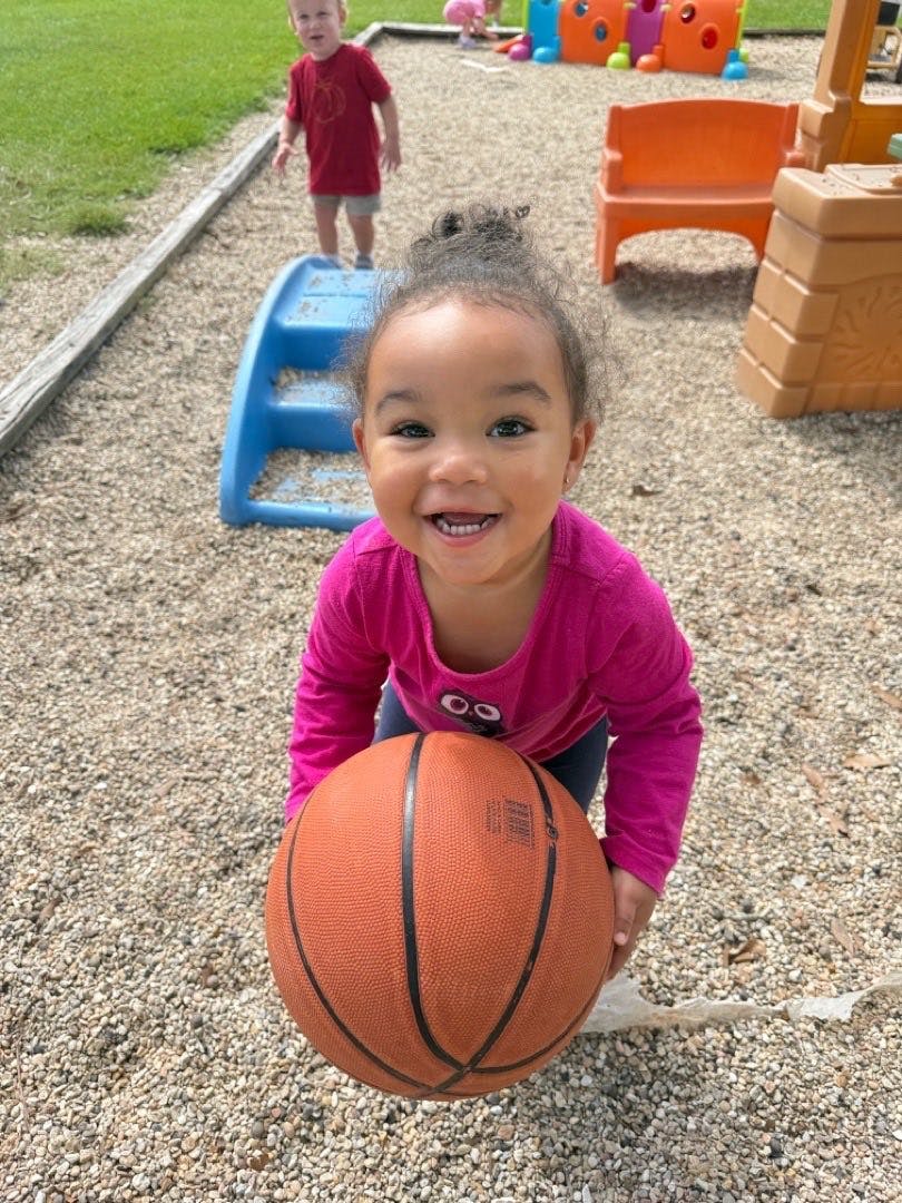 Child holding a basketball at a playground