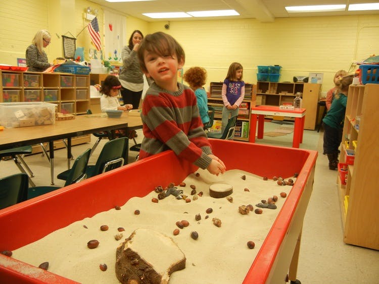 Child playing in a sand table in a classroom
