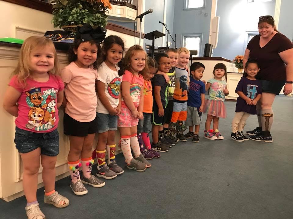 Group of children and an adult standing in a line indoors