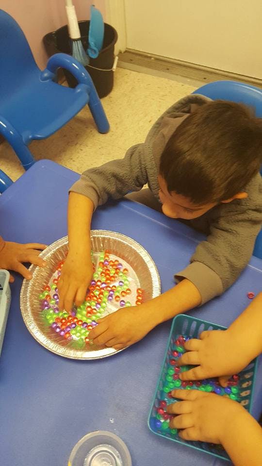 Child playing with colorful beads in a foil pie plate