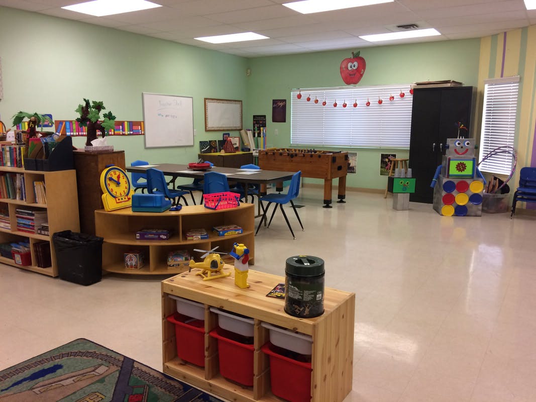 Classroom with tables, chairs, bookshelves, and a foosball table