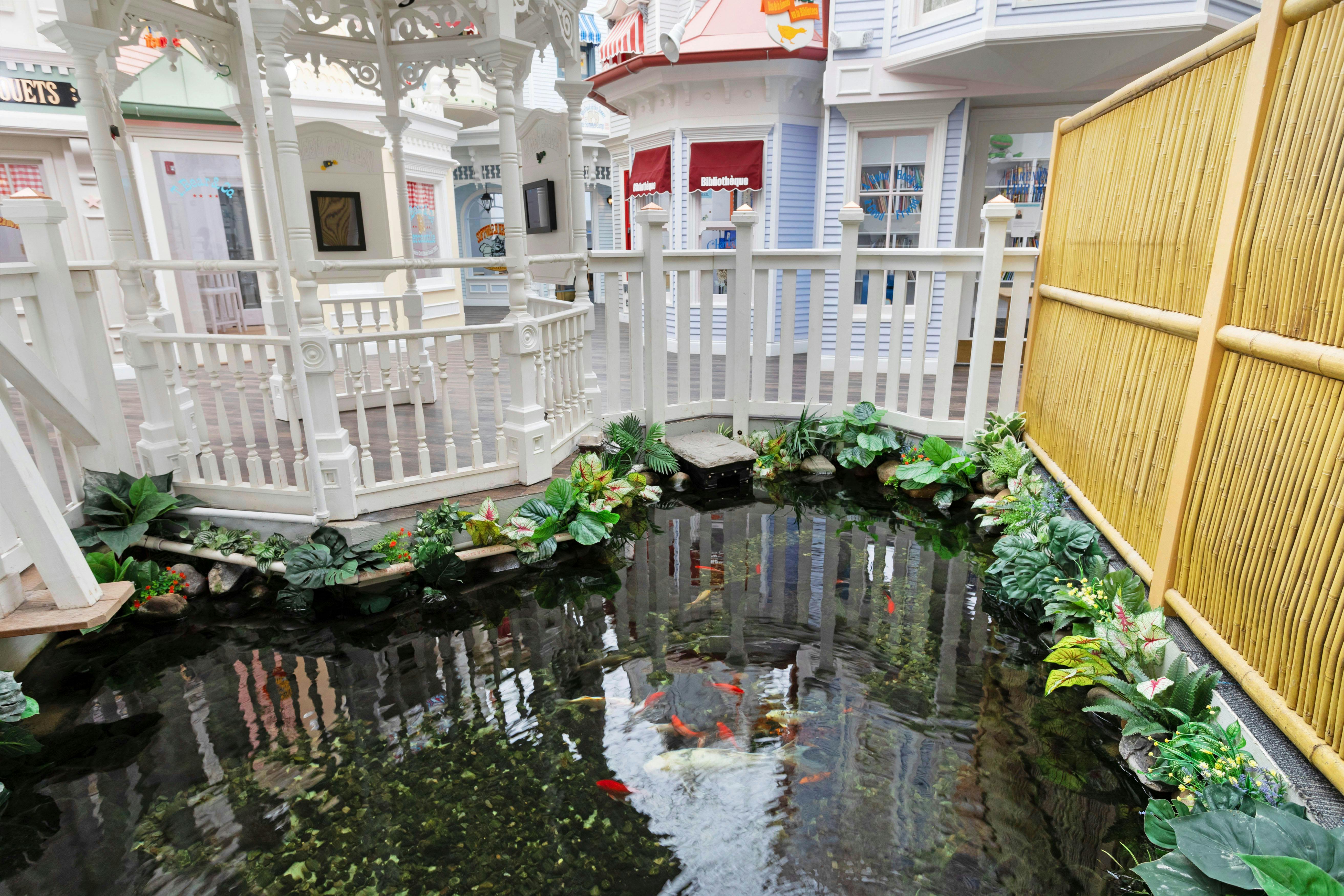 Decorative koi pond with plants and a white gazebo in a miniature village