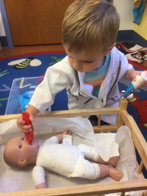 Child playing with a doll in a crib
