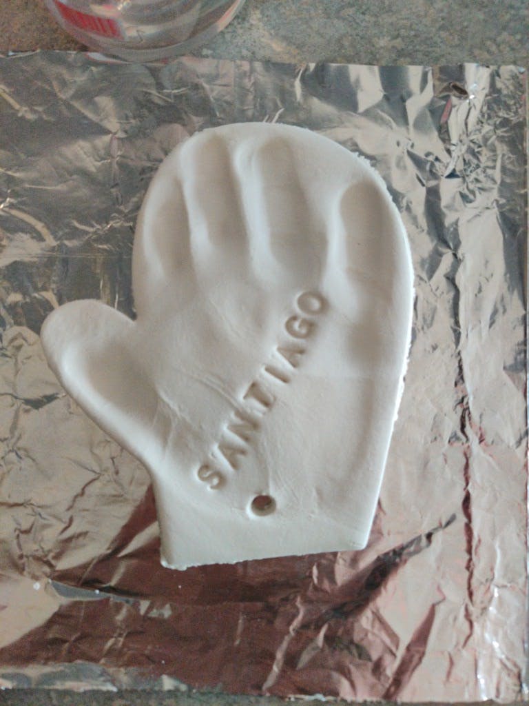 White mitten-shaped object with the name SANTIAGO on it