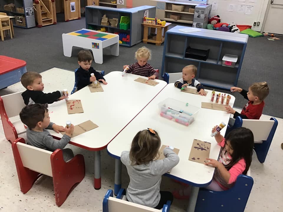 Children sitting at tables doing crafts in a classroom