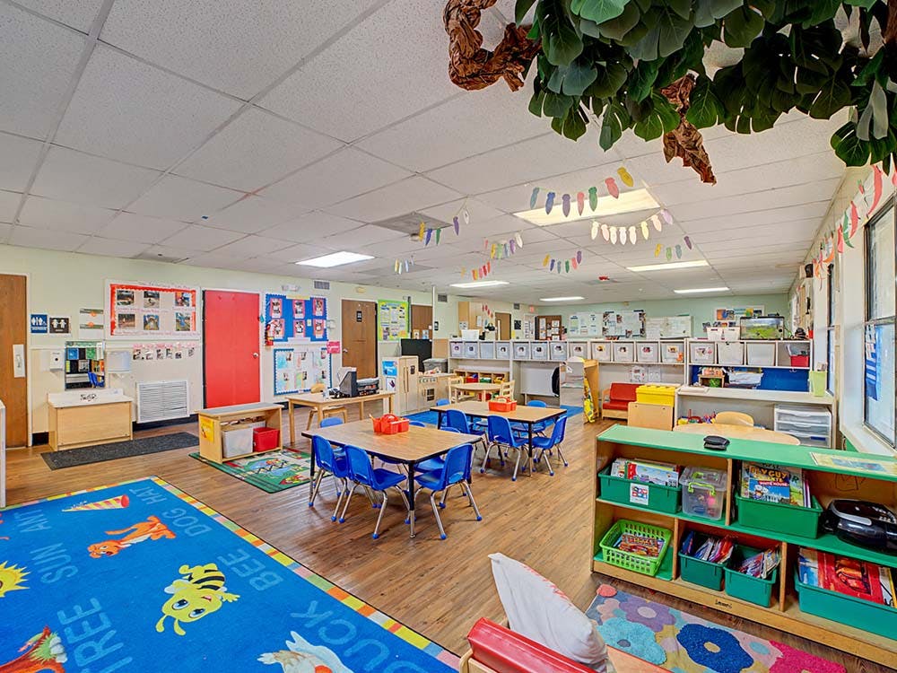 Empty children's classroom with small tables and chairs