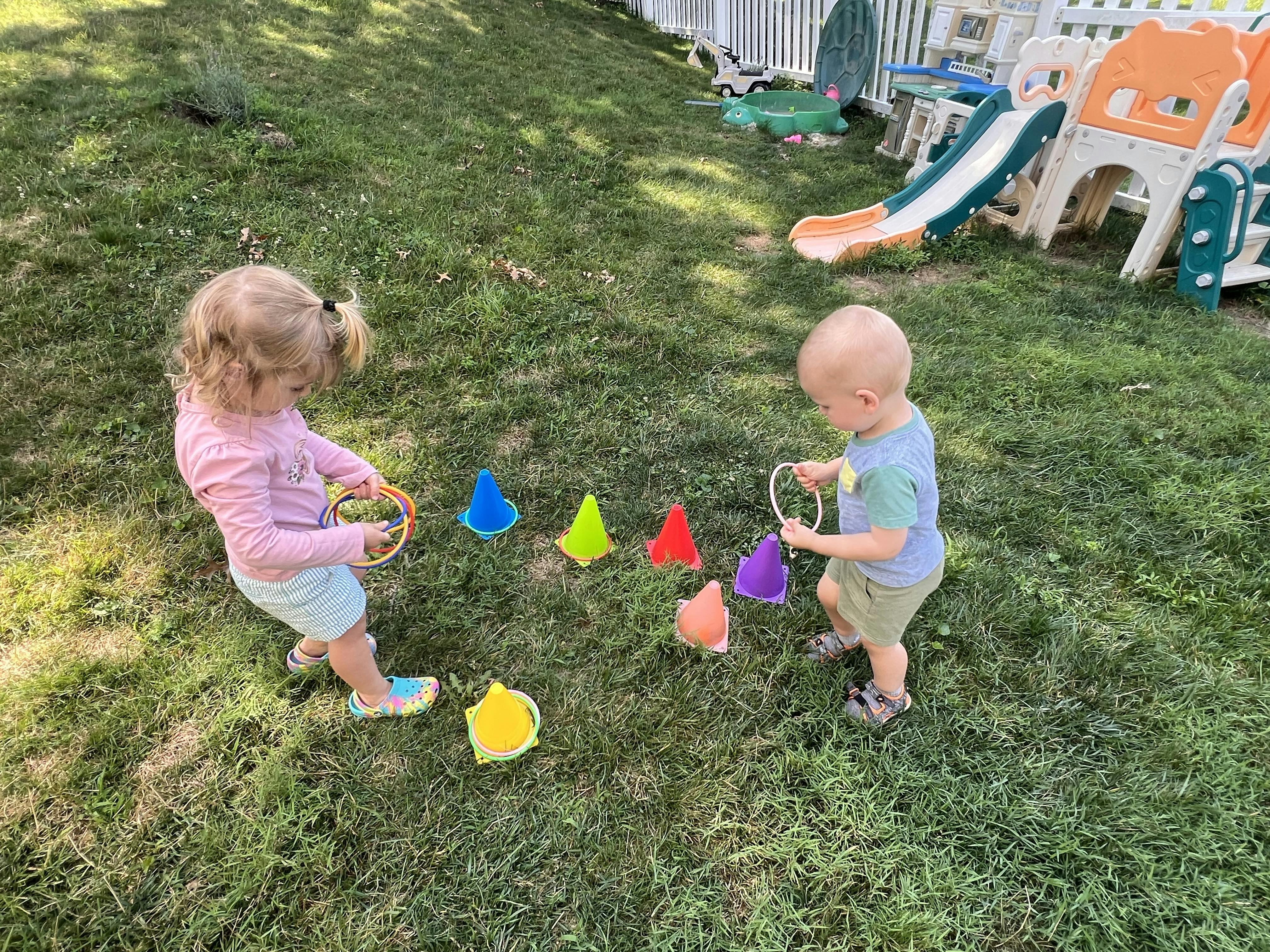 Two children playing a ring toss game on the lawn