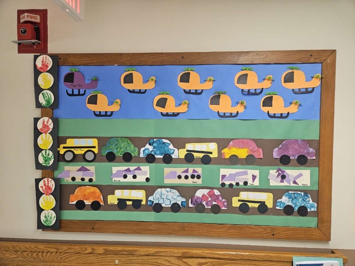 Bulletin board with paper cutouts of helicopters, cars, and trucks