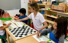 Adult and children at a table with a chessboard and papers