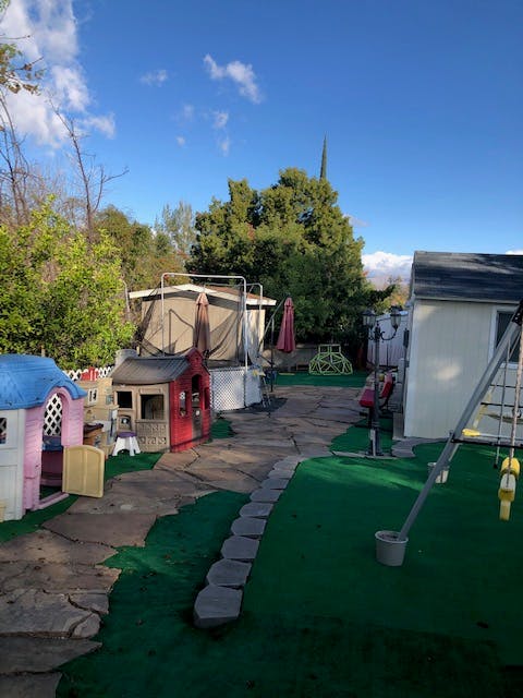 Backyard with playhouses, trampoline, and swing set