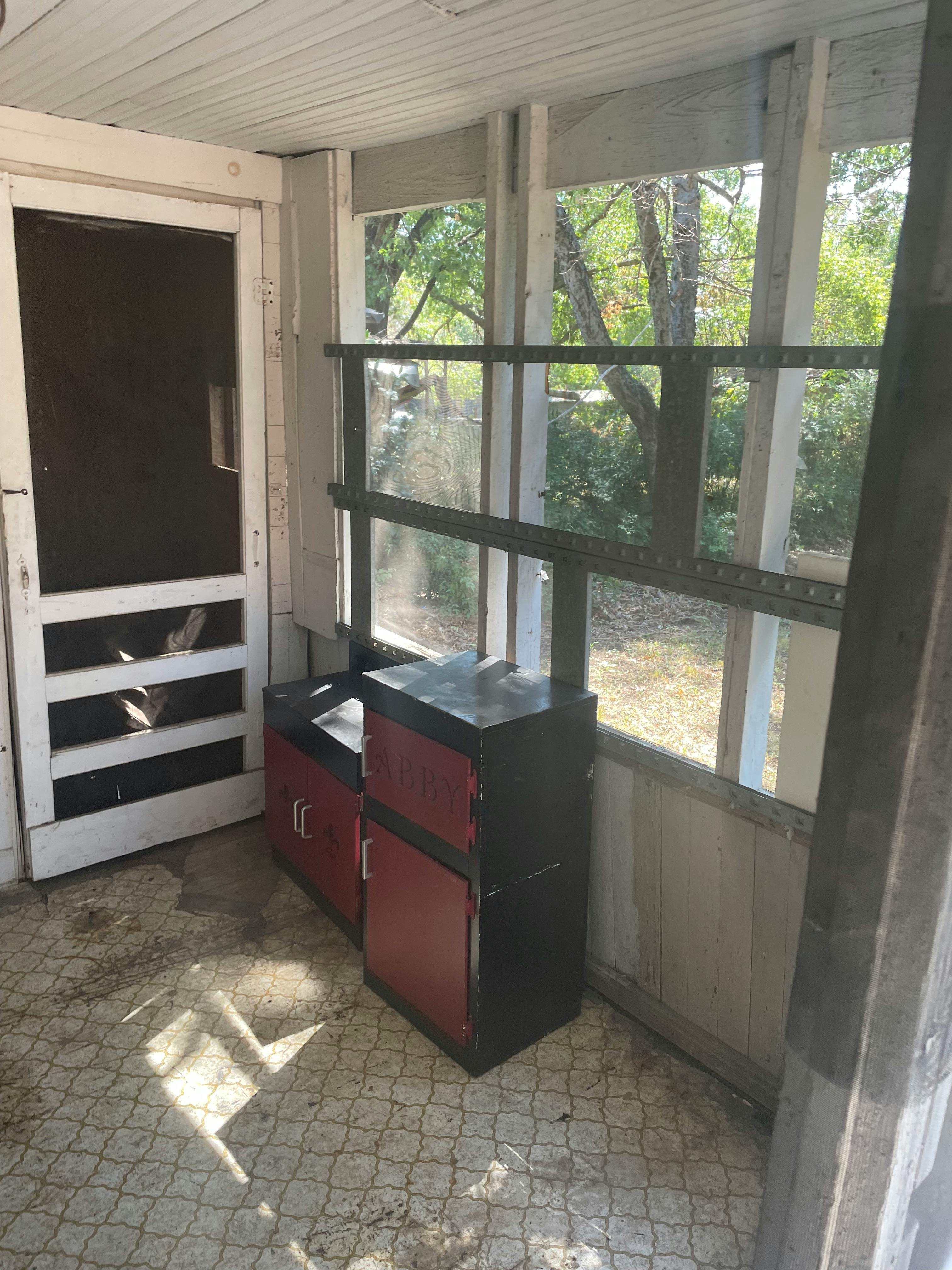 Screened-in porch with a broken screen door and red cabinets