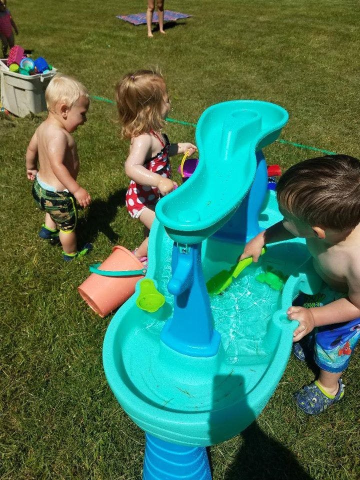 Three children playing with a water table outdoors