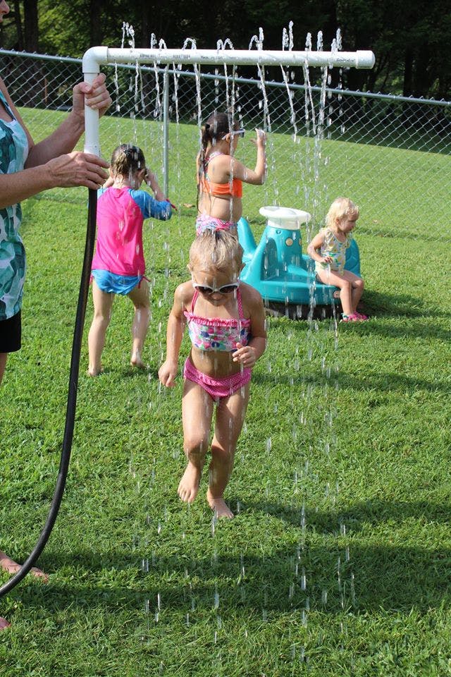 Children playing in water from a PVC pipe sprinkler