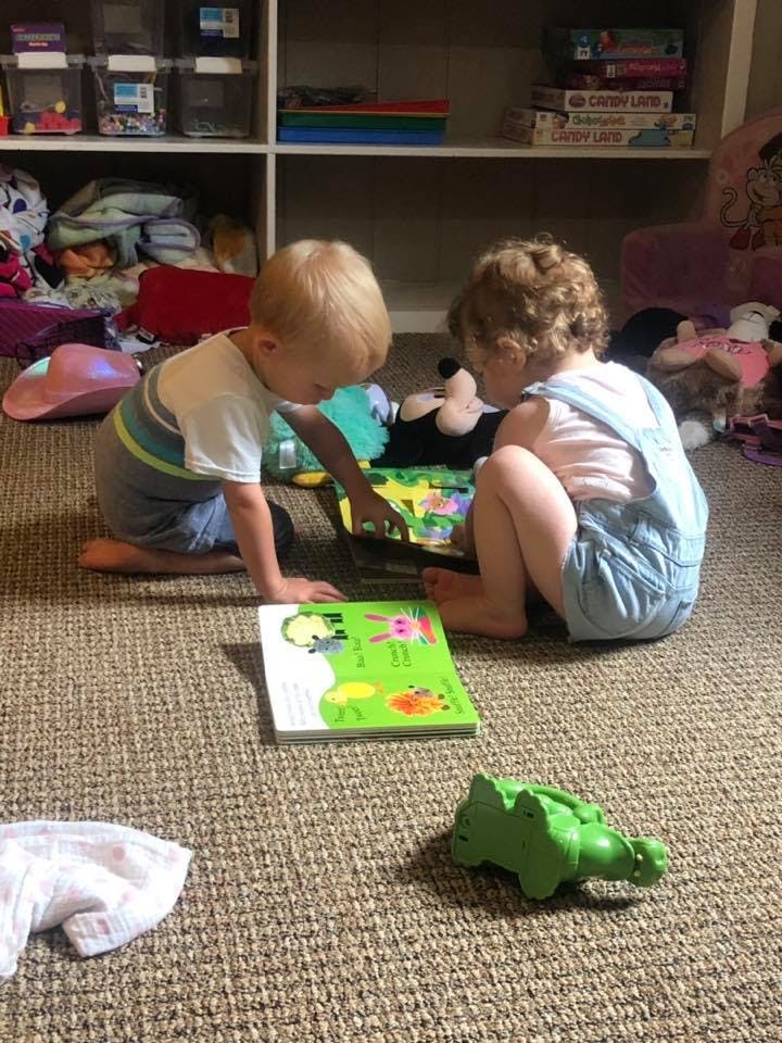 Two children on the floor looking at a book