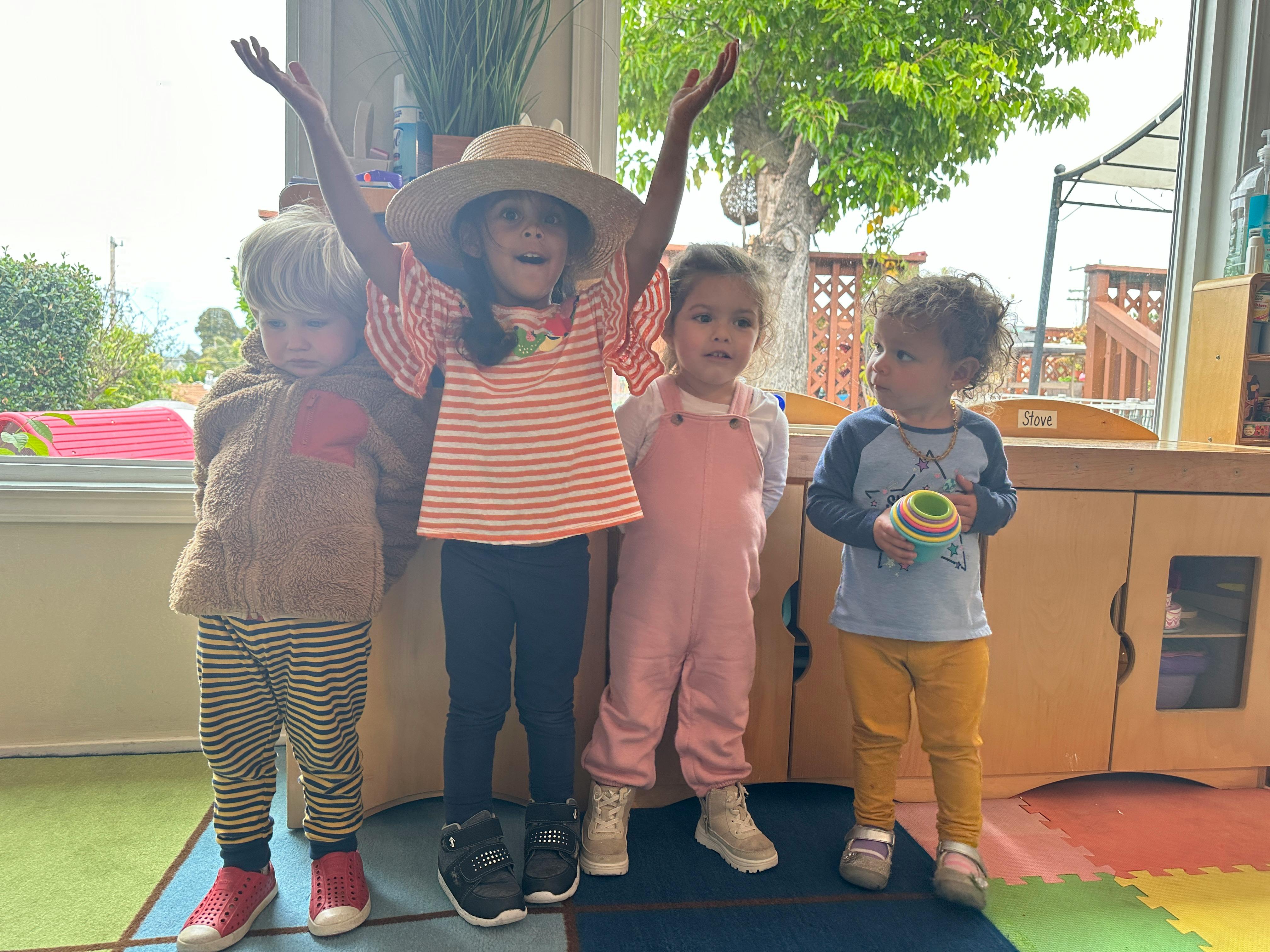Four children standing together, one with arms raised